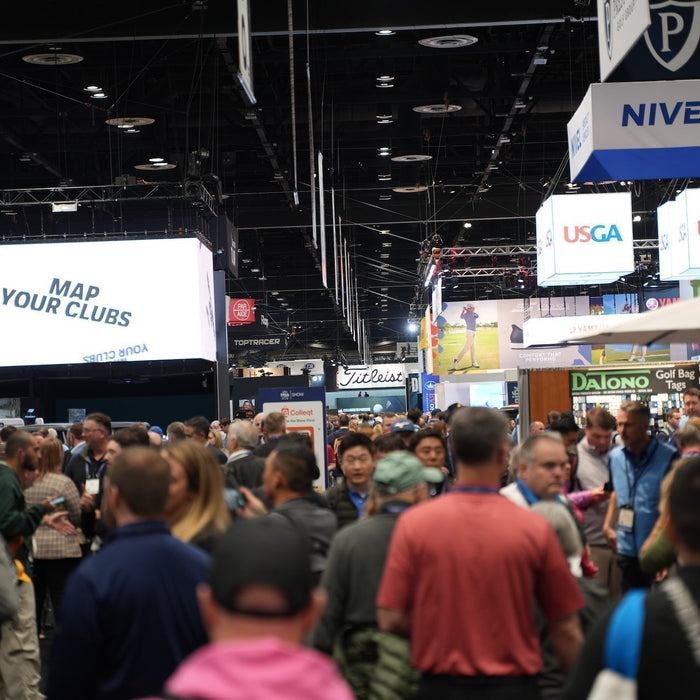 The 2025 PGA Show product display floor with many golf brand logo signs and patrons walking among the displays