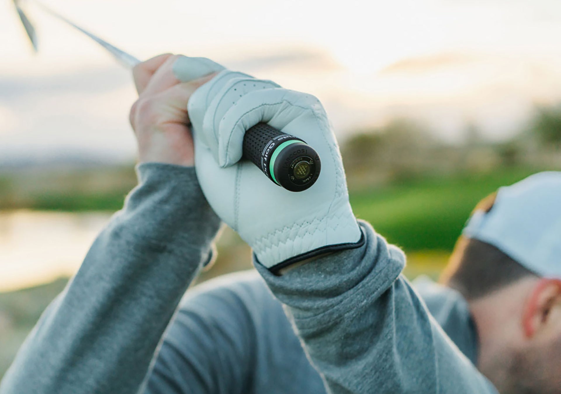 A golfer with a club over his shoulder with an Arccos Smart Sensor on the end of it