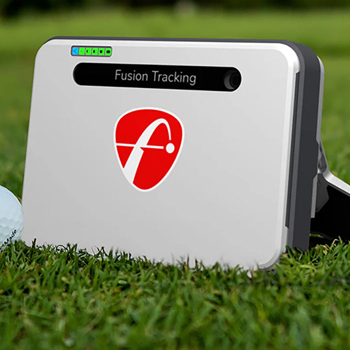 The 2024 FlightScope Mevo+ sitting on the golf course with a golf ball next to it