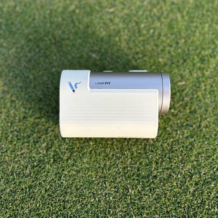 The Voice Caddie Laser FIT golf rangefinder sitting on its side on a golf hitting mat