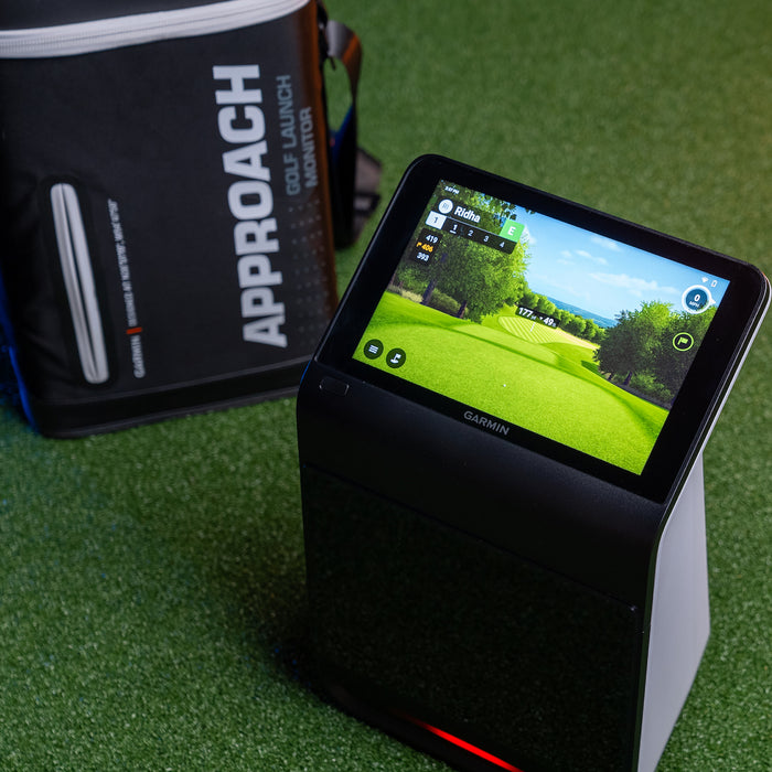 The Garmin Approach R50 golf launch monitor with Home Tee Hero simulator software on the display and the carrying case behind it on a golf hitting mat