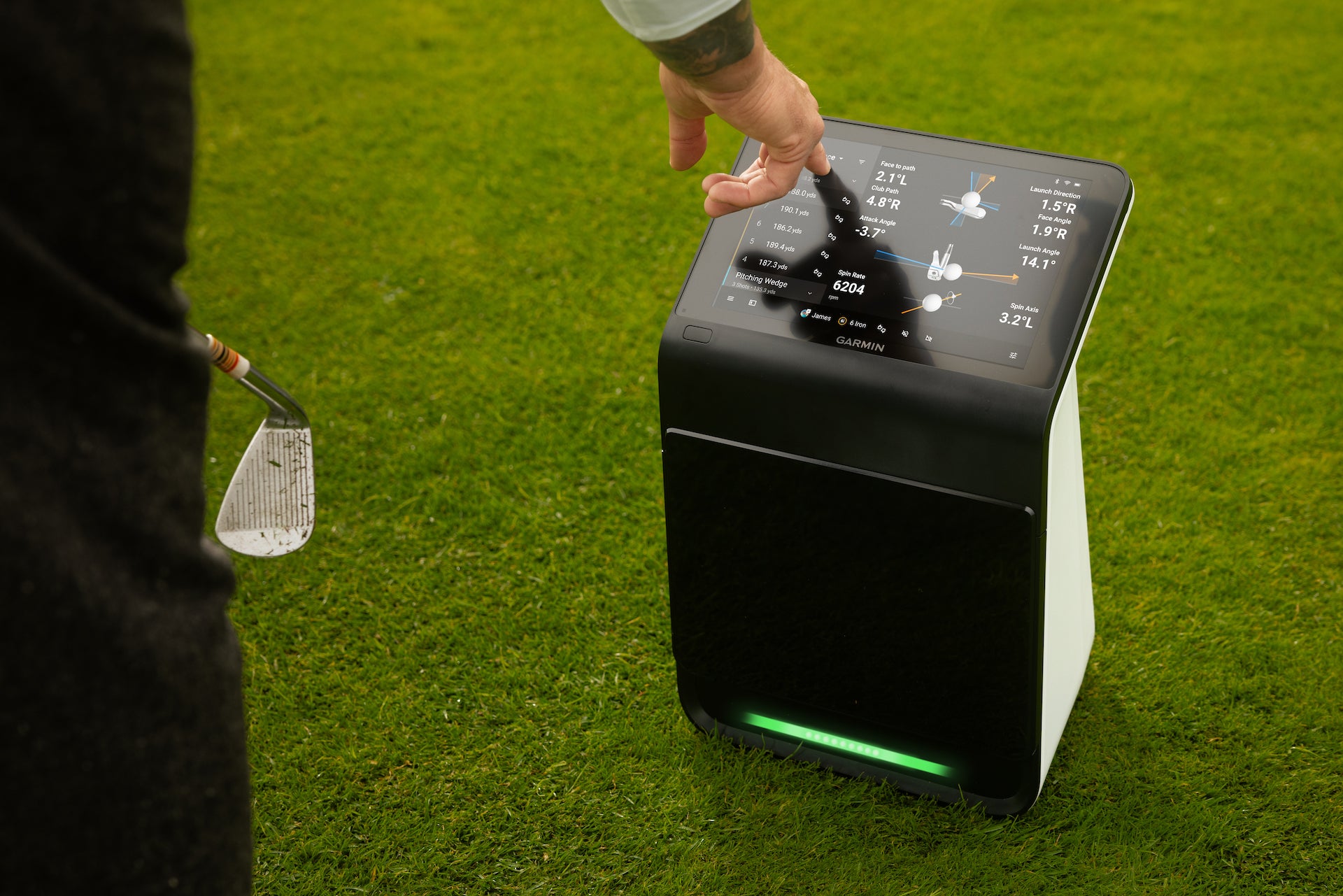 A golfer tapping the data on the touchscreen display of the Garmin Approach R50 on the golf course