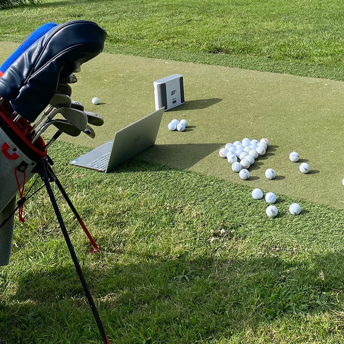 The SkyTrak+ at the golf range with a laptop, golf bag and many golf balls (image by PlayBetter golf reviewer Marc)