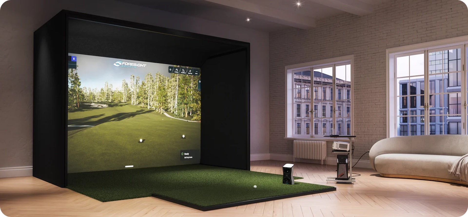 The Foresight Sports QuadMAX launch monitor in an indoor golf simulator in a room with large windows in the city and a sofa