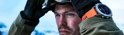 A man dressed in winter wear getting ready to pull down goggles with an orange-strapped Garmin fenix 7 watch on his wrist