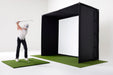 A golfer swinging on a golf hitting mat in front of a PlayBetter SimStudio enclosure